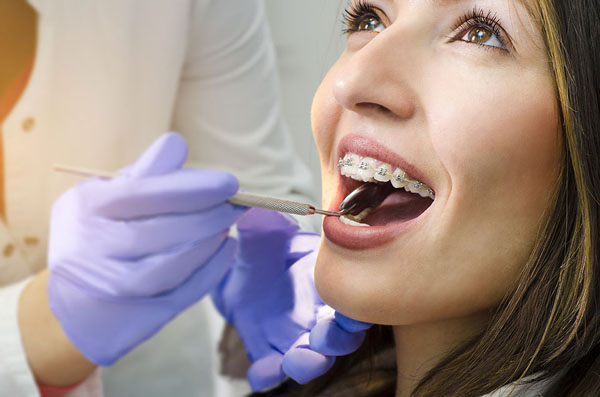 young girl who has braces getting her teeth checked at the dentist