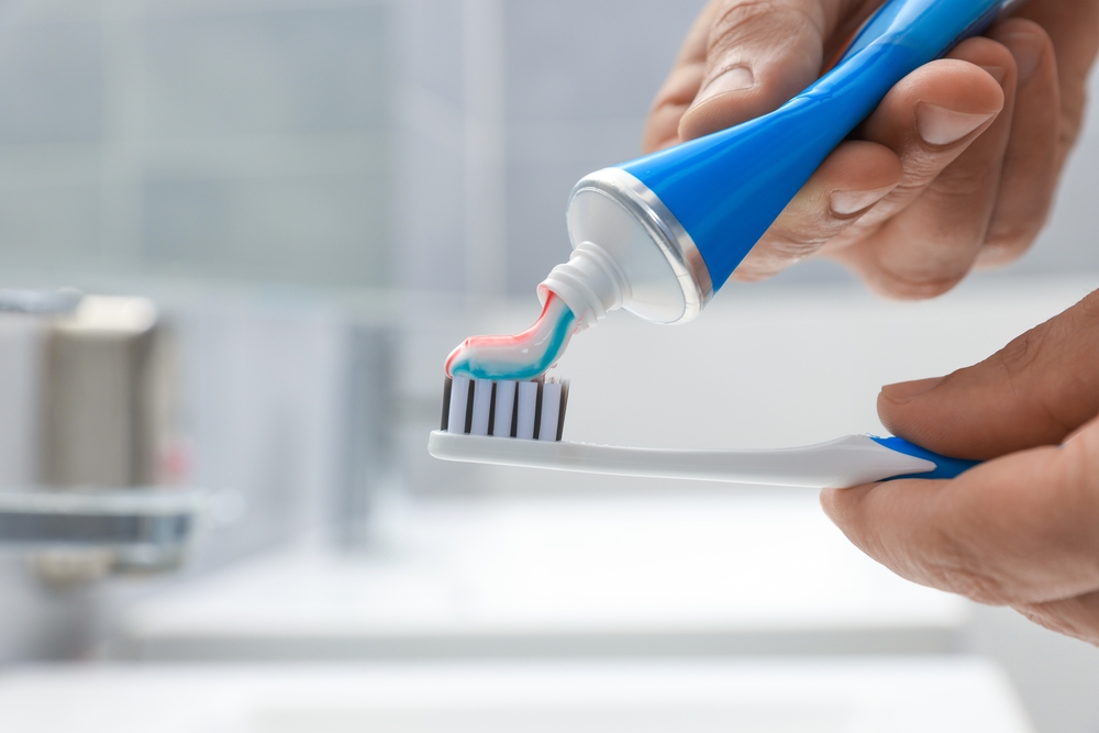 toothpaste being squeezed onto toothbrush
